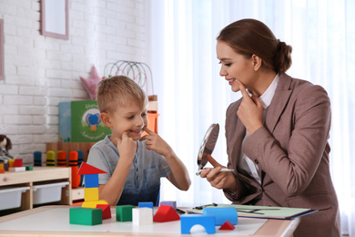 Speech therapist working with little boy in office