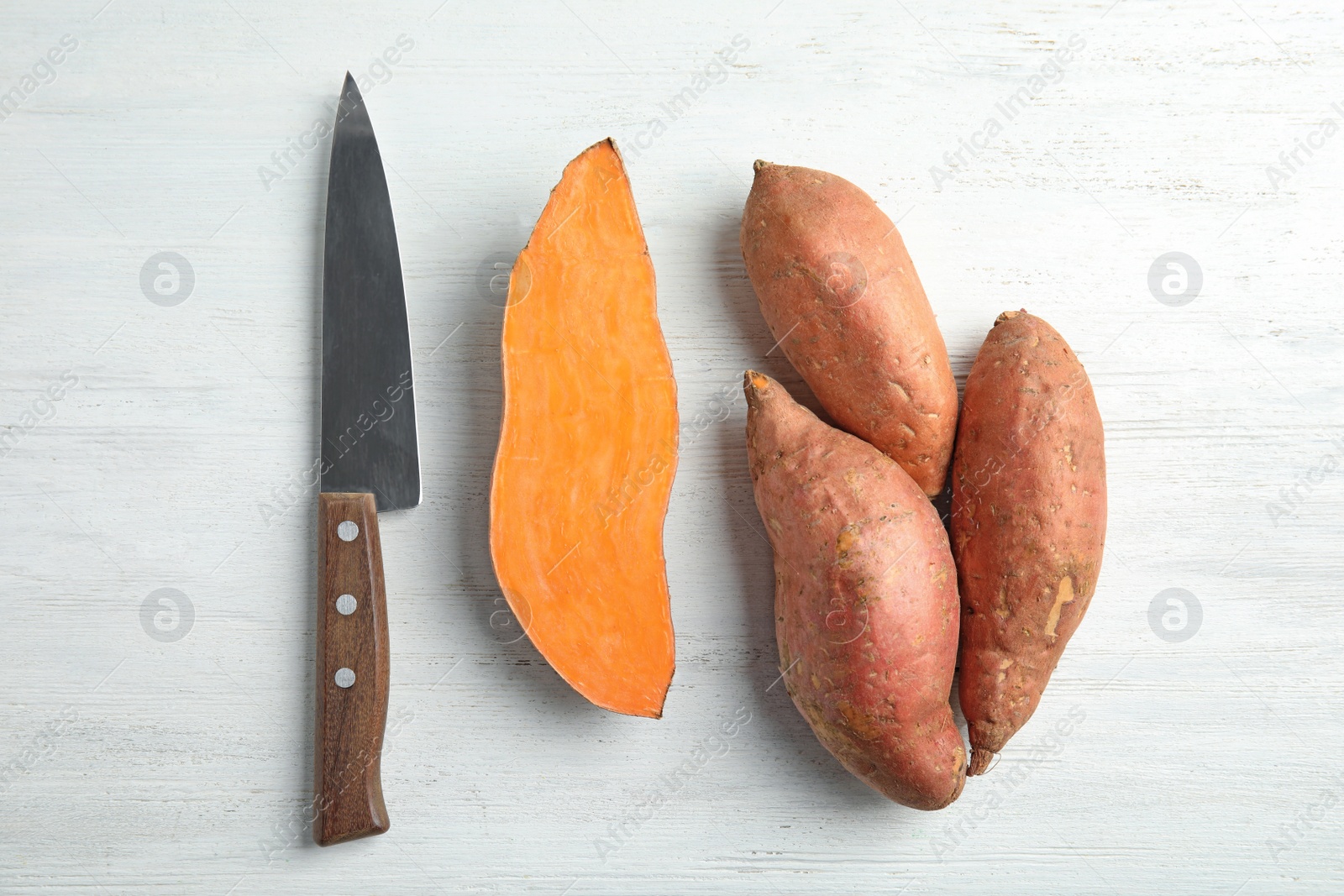 Photo of Flat lay composition with sweet potatoes and knife on white wooden background