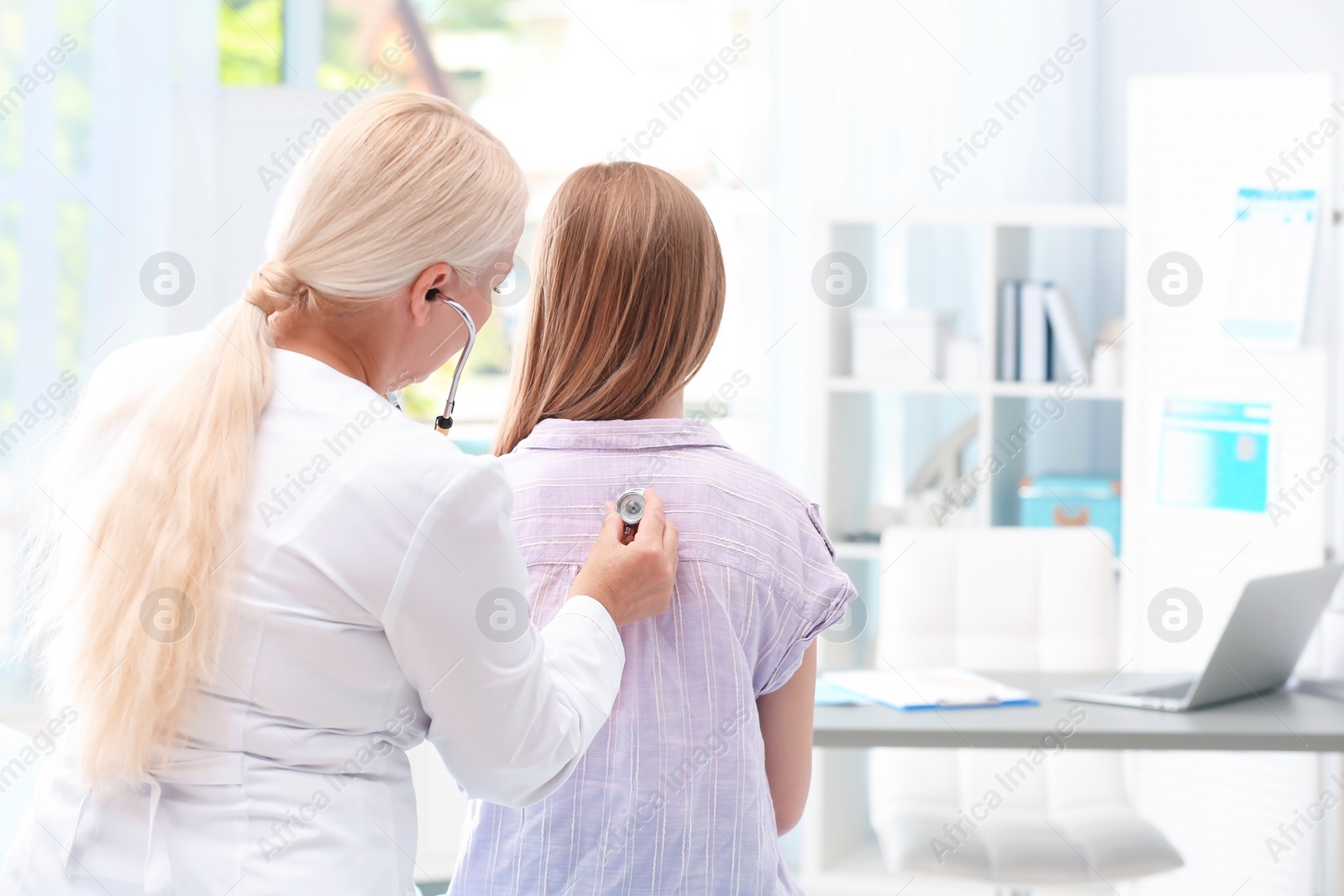 Photo of Doctor examining coughing teenage girl at clinic