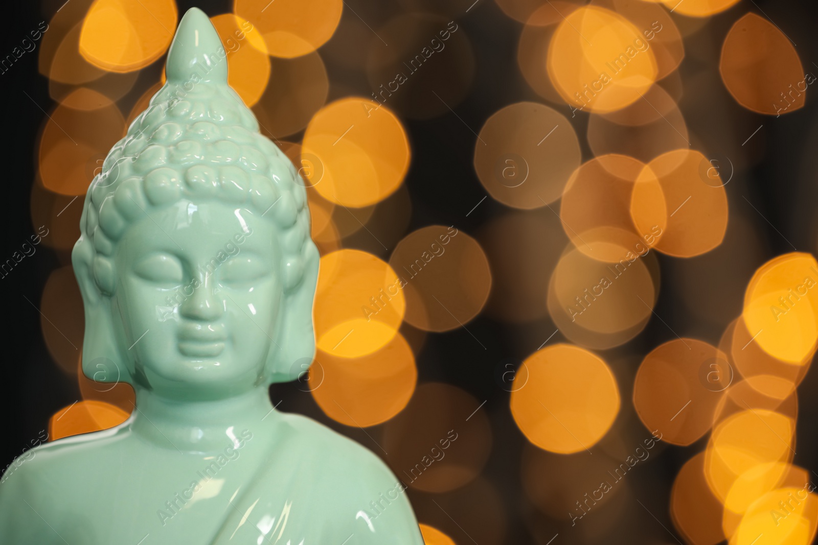 Photo of Buddha statue against blurred lights, closeup. Space for text