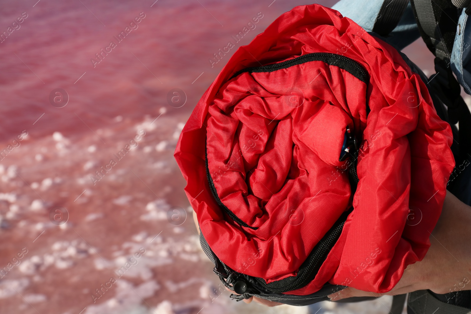 Photo of Woman with sleeping bag on coast of pink lake