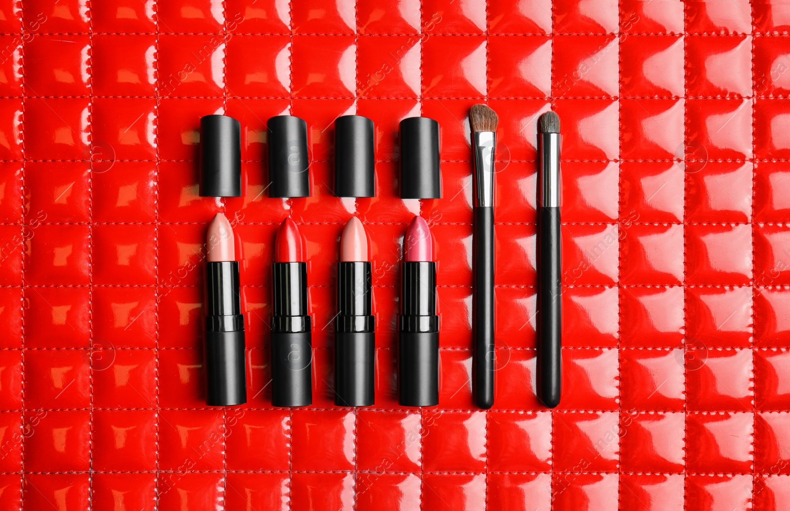 Photo of Flat lay composition with lipsticks and cosmetic brushes on color background