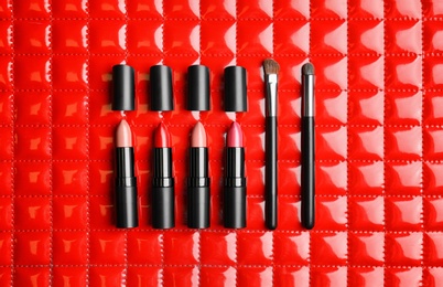 Flat lay composition with lipsticks and cosmetic brushes on color background