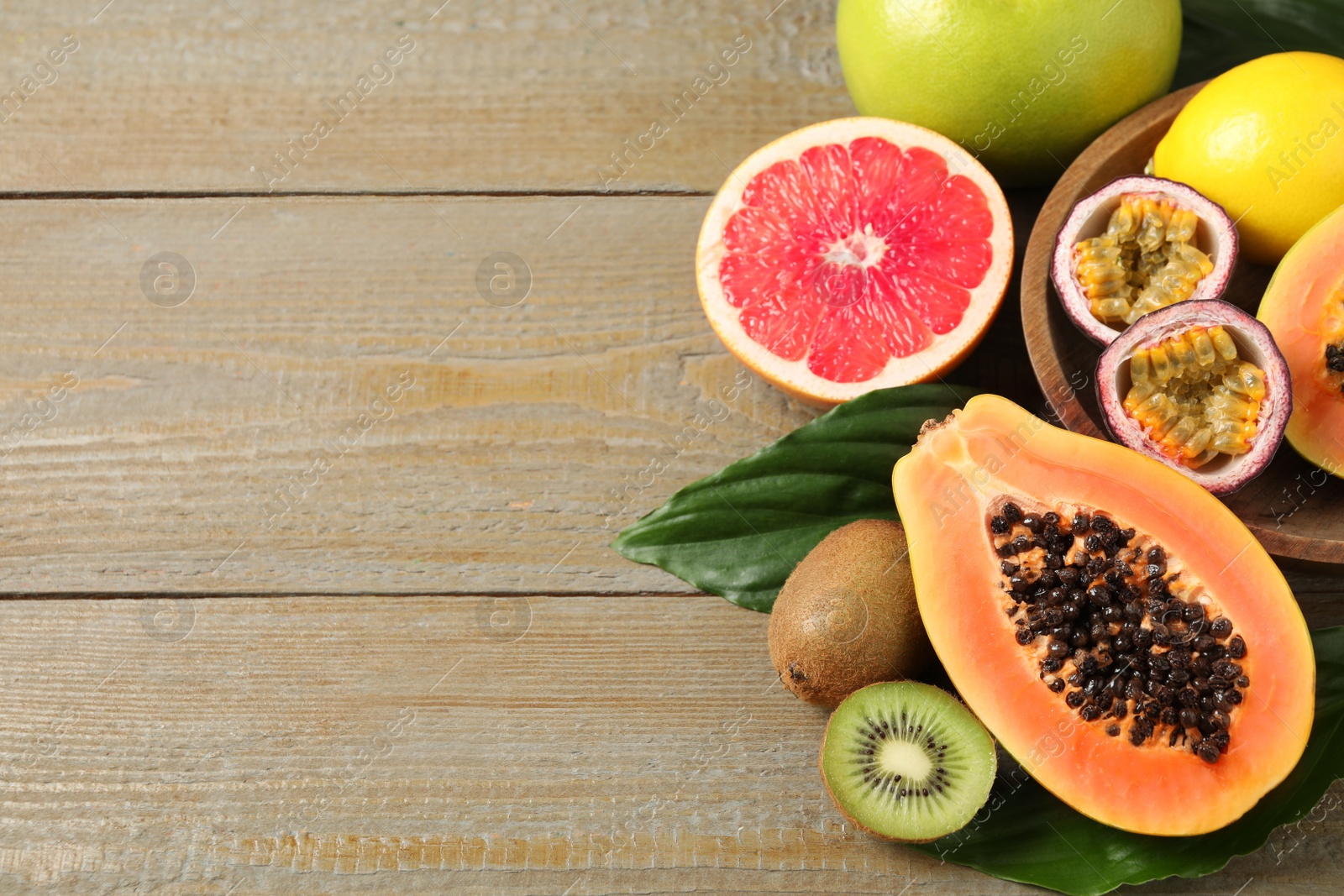 Photo of Fresh ripe papaya and other fruits on wooden table, above view. Space for text