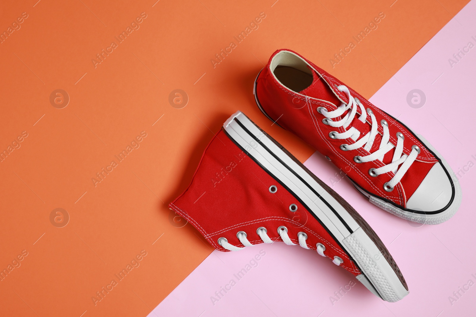 Photo of Pair of new stylish red sneakers on colorful background, flat lay. Space for text