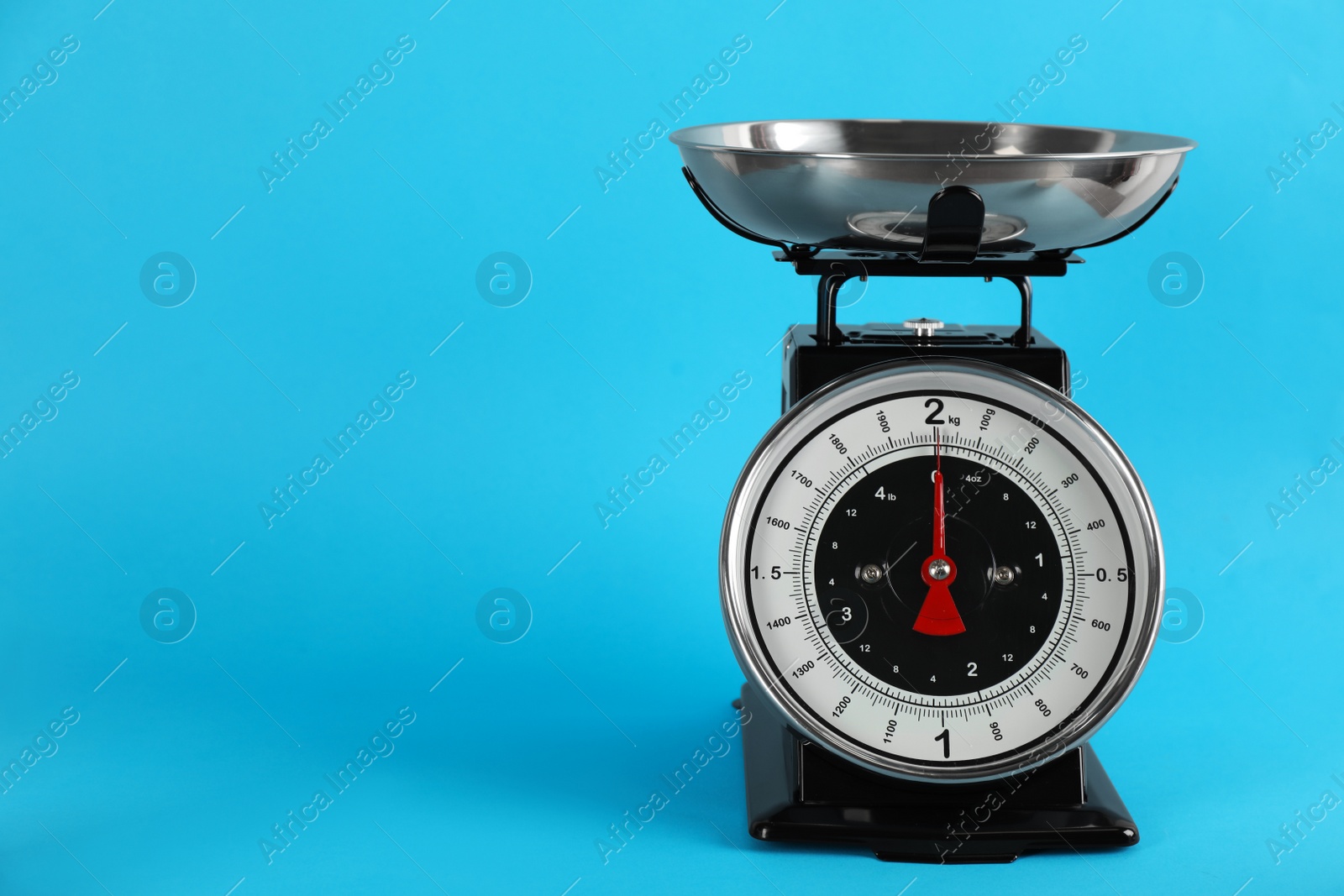 Photo of Retro mechanical kitchen scale on light blue background, space for text