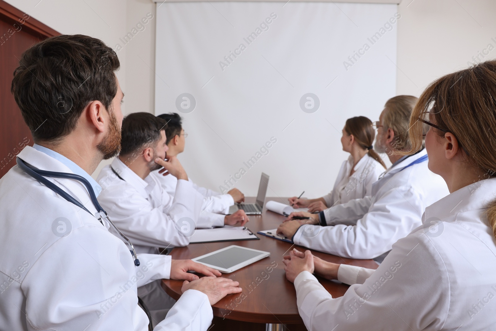 Photo of Team of doctors using video projector during conference indoors