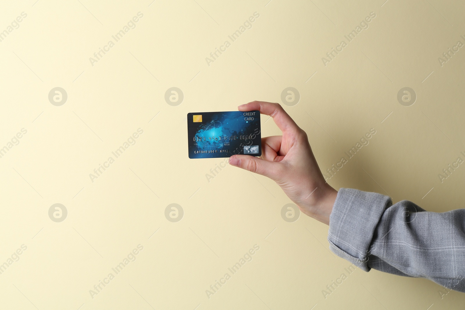 Photo of Woman holding credit card on beige background, closeup