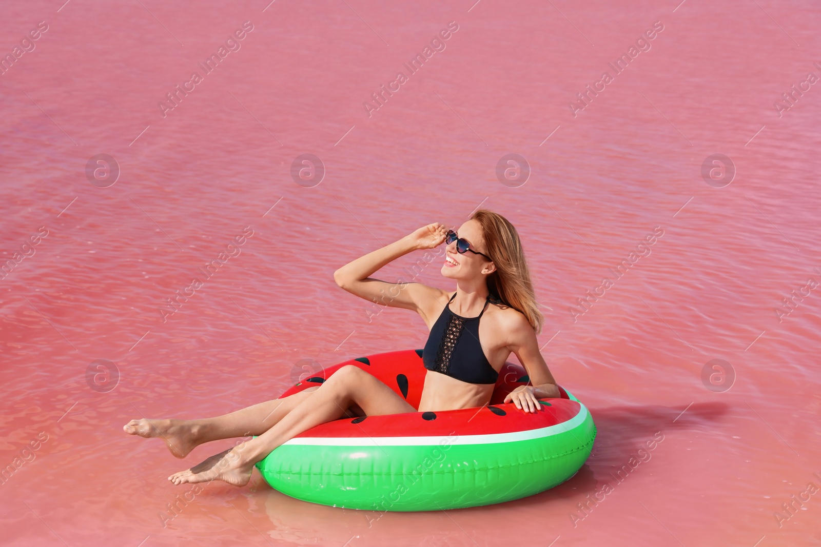 Photo of Beautiful woman on inflatable ring in pink lake