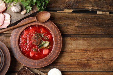 Photo of Stylish brown clay plate with Ukrainian borsch served on wooden table, flat lay. Space for text