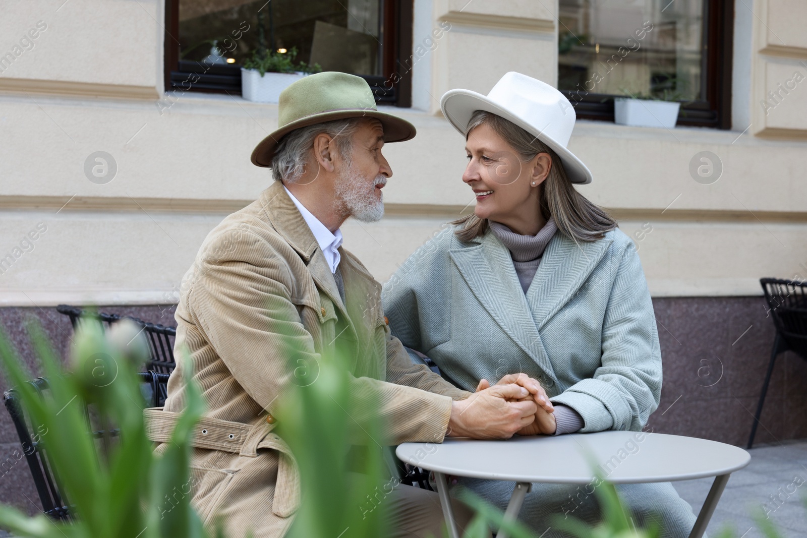 Photo of Portrait of affectionate senior couple sitting in outdoor cafe