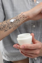 Tattooed woman with jar of cream, closeup view