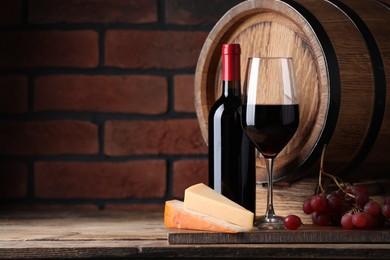Delicious wine, cheese, grapes and wooden barrel on table against brick wall. Space for text