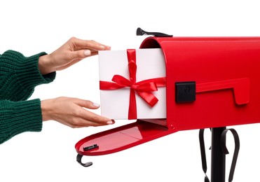 Photo of Woman putting Christmas gift into mailbox on white background, closeup. Sending present by mail