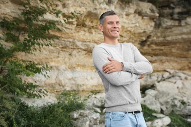 Man in stylish sweater near old cliff