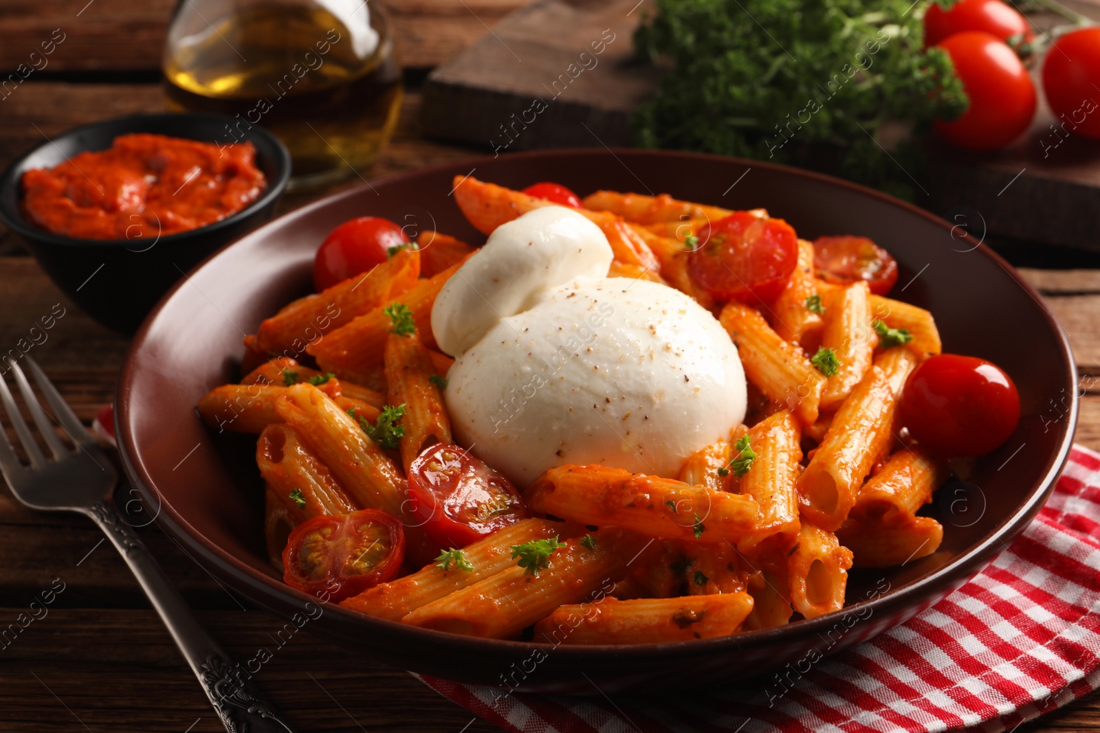 Photo of Delicious pasta with burrata cheese and tomatoes on wooden table, closeup