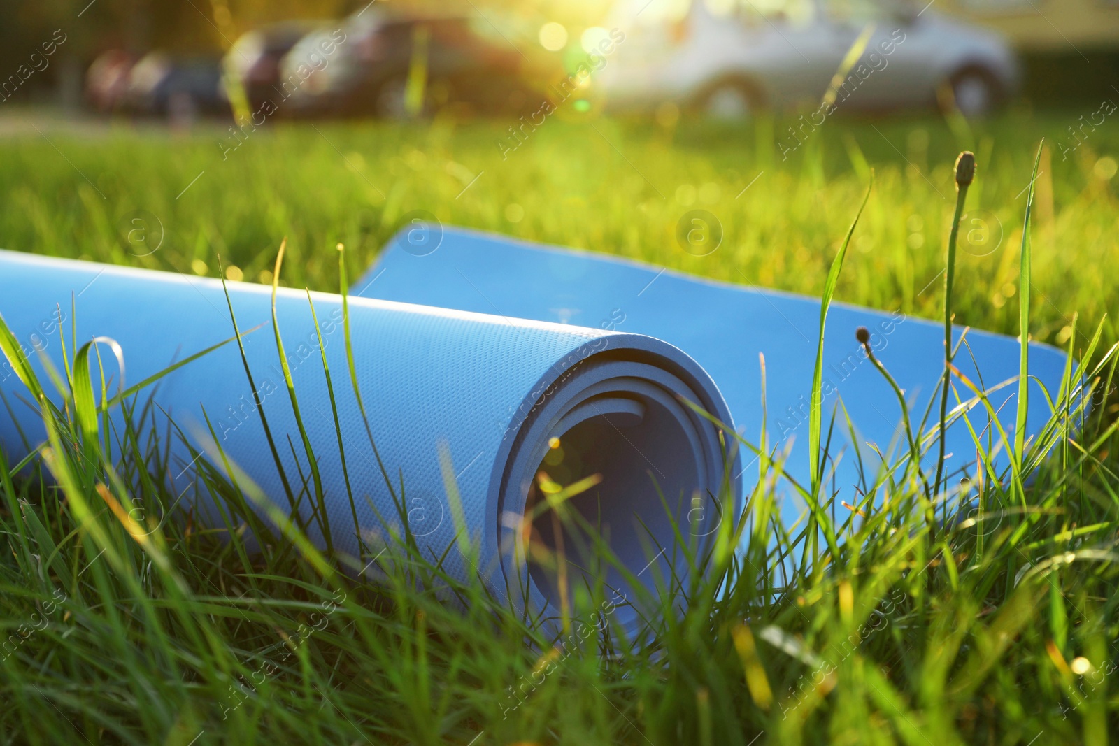 Photo of Blue karemat or fitness mat in fresh green grass outdoors, closeup