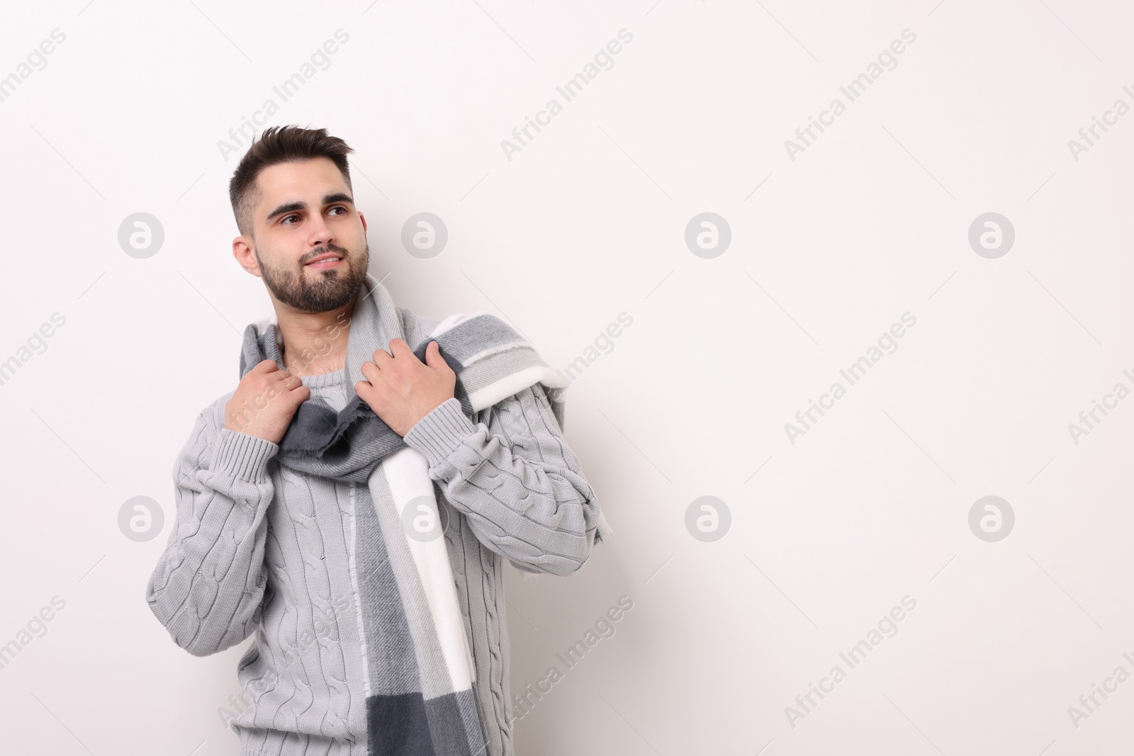 Photo of Portrait of smiling man in warm scarf on light background. Space for text