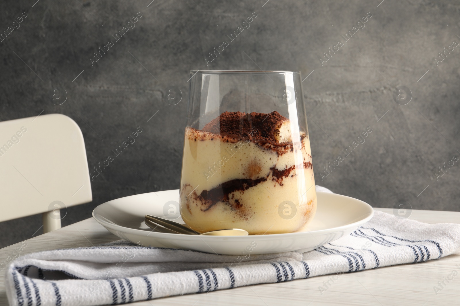 Photo of Delicious tiramisu in glass on white wooden table