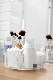 Organizer with cosmetic products on wooden table in bathroom