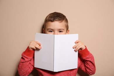 Photo of Cute little boy with book on color background