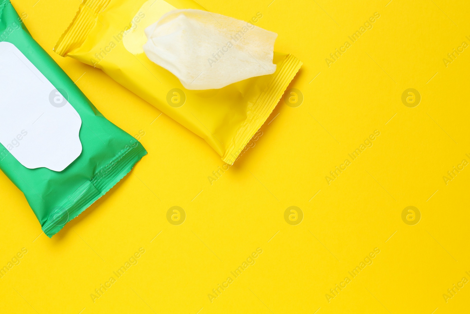 Photo of Wet wipes flow packs on yellow background, flat lay. Space for text