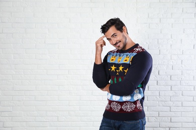 Photo of Portrait of happy man in Christmas sweater near white brick wall. Space for text