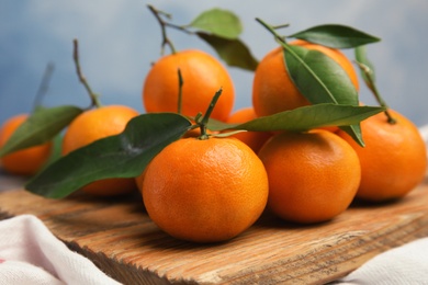 Photo of Wooden board with fresh ripe tangerines on table