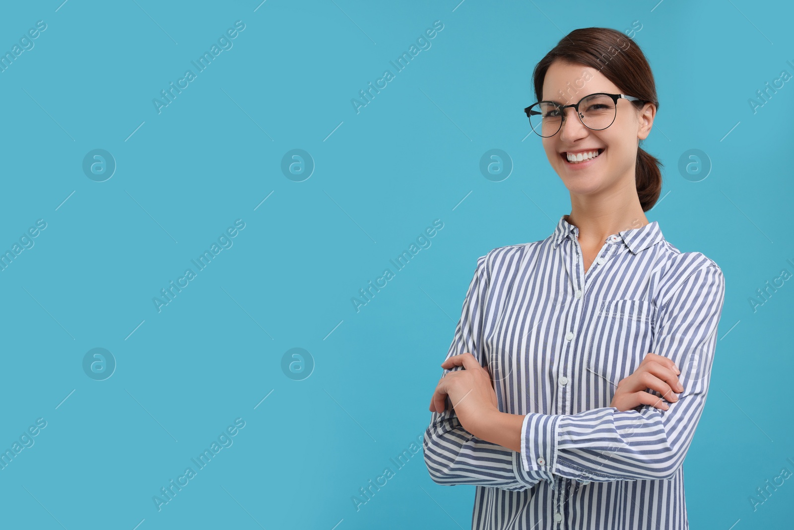 Photo of Happy secretary with crossed arms on light blue background, space for text