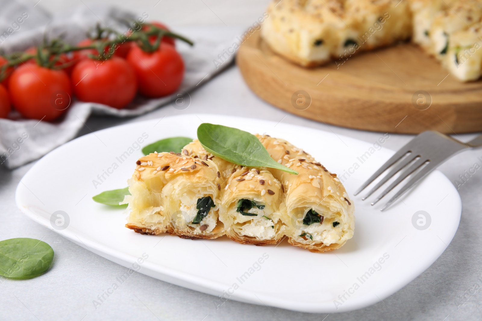 Photo of Piece of delicious puff pastry with spinach on light table, closeup