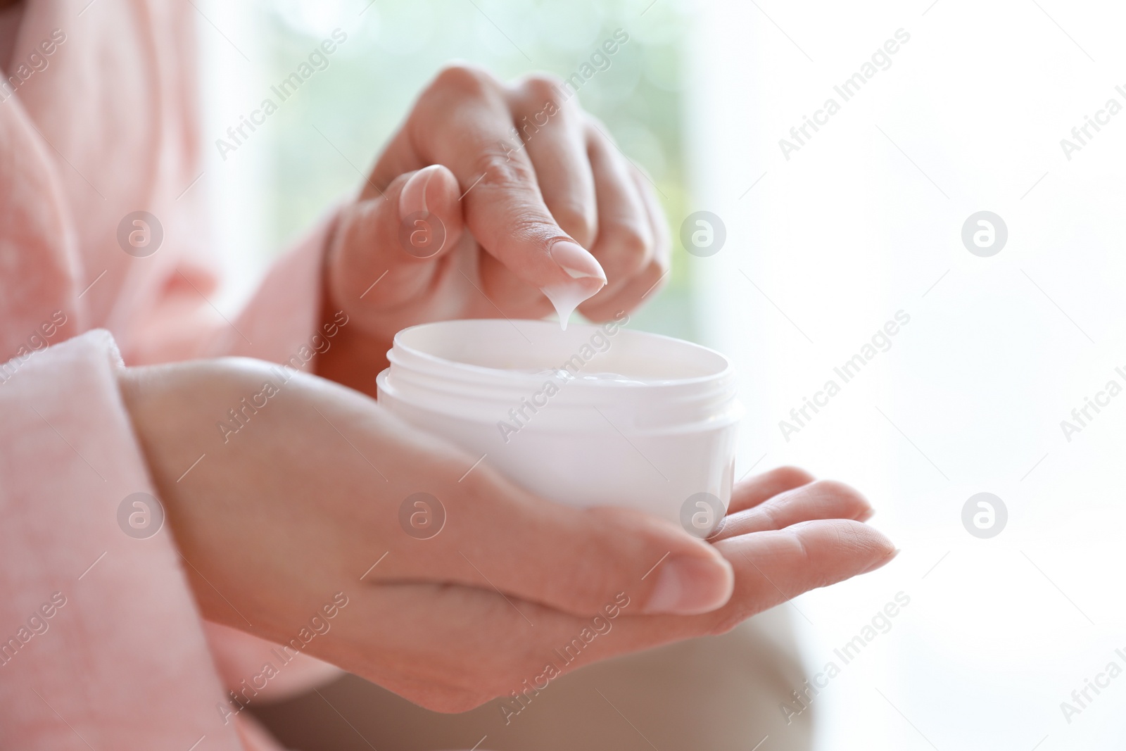 Photo of Woman with jar of moisturizing cream on blurred background, closeup