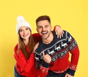 Photo of Couple wearing Christmas sweaters on yellow background