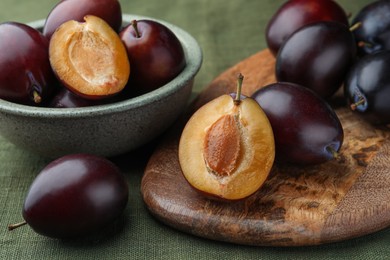 Photo of Many tasty ripe plums on green fabric