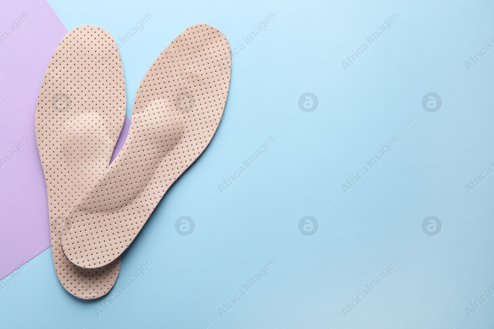 Photo of Beige orthopedic insoles on color background, flat lay. Space for text