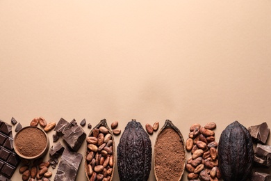 Flat lay composition with cocoa pods and chocolate on beige background, space for text