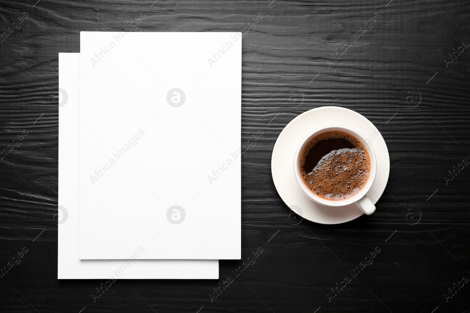 Photo of Blank paper sheets for brochure and cup of coffee on black wooden background, flat lay. Mock up