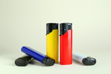 Photo of Stylish small pocket lighters on beige background