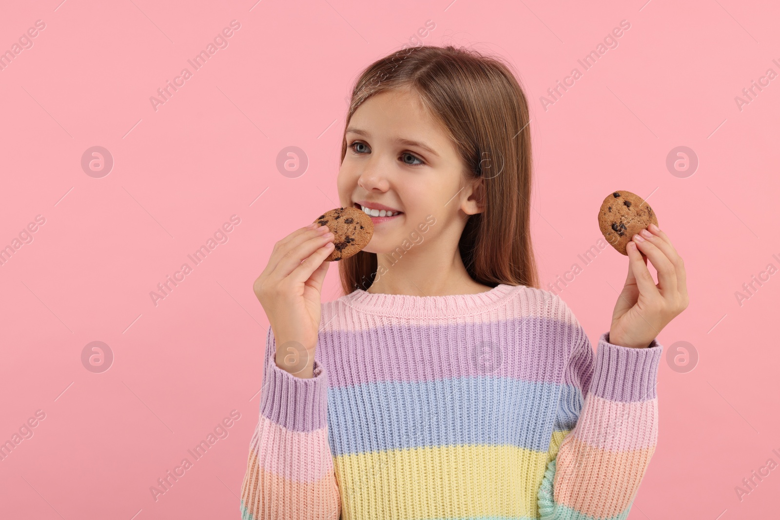 Photo of Cute girl with chocolate chip cookies on pink background