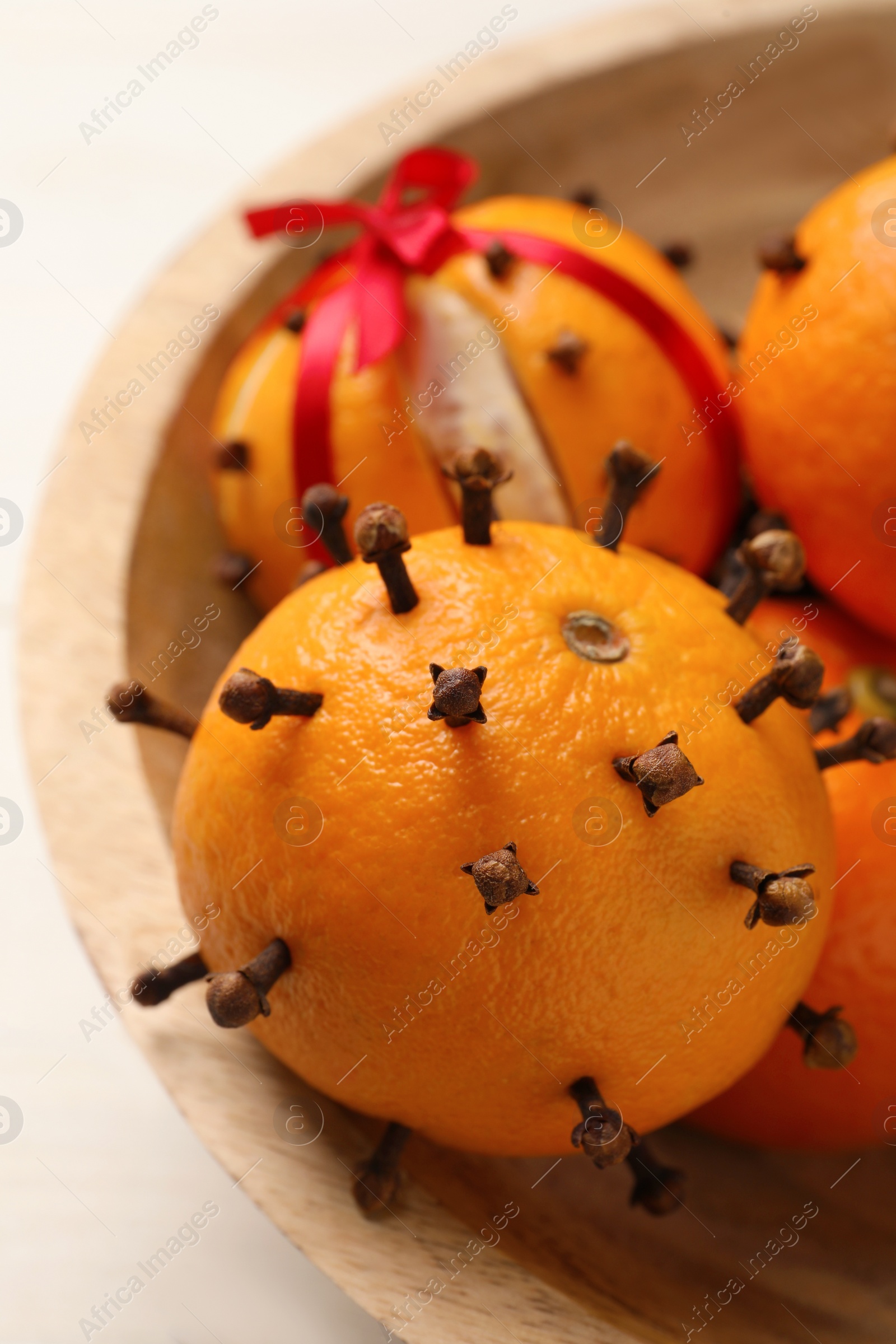 Photo of Pomander balls made of tangerines with cloves on white wooden table, closeup
