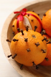 Pomander balls made of tangerines with cloves on white wooden table, closeup