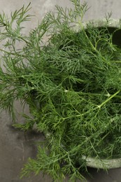 Fresh green dill in bowl on grey table, top view