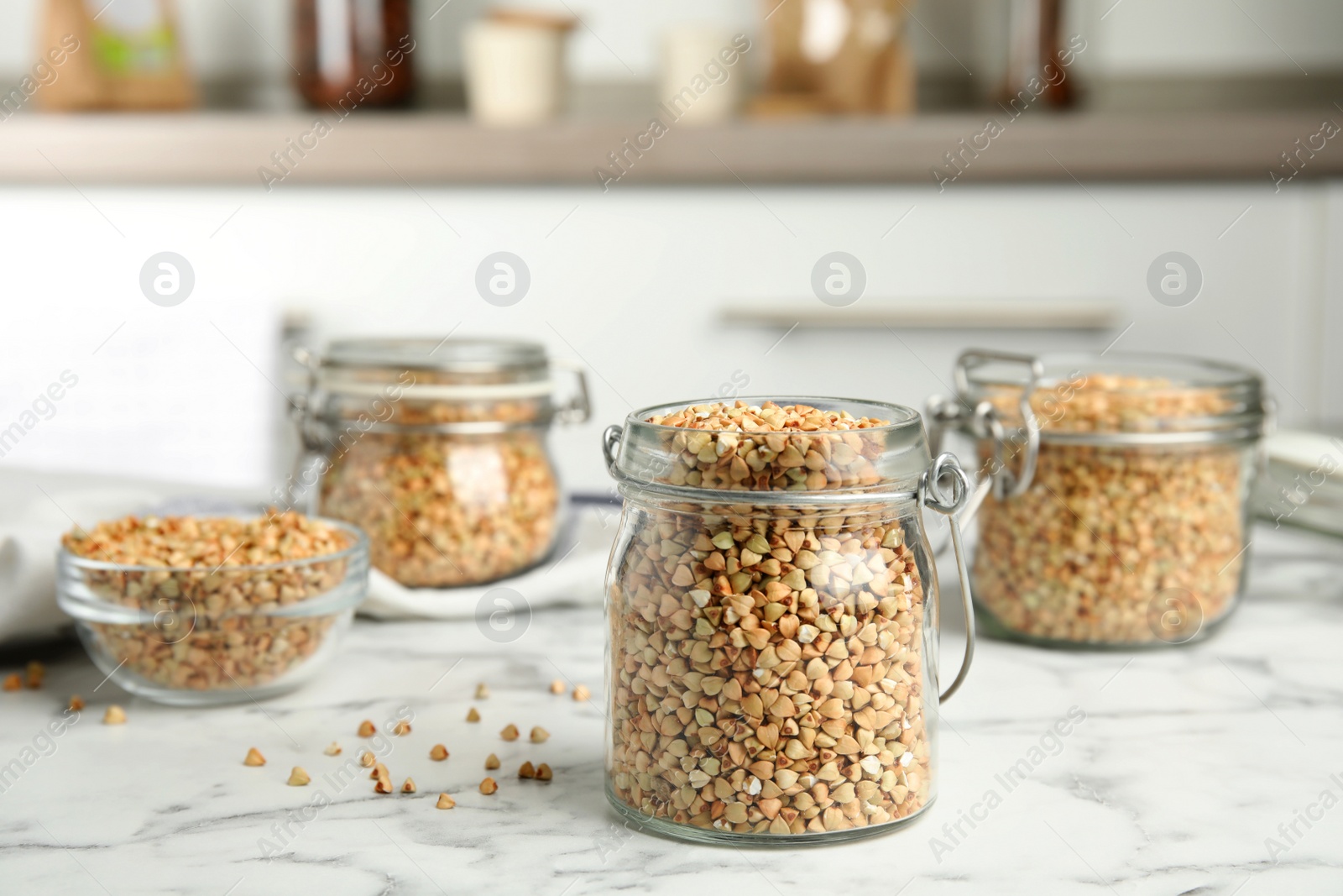 Photo of Uncooked green buckwheat grains on white marble table