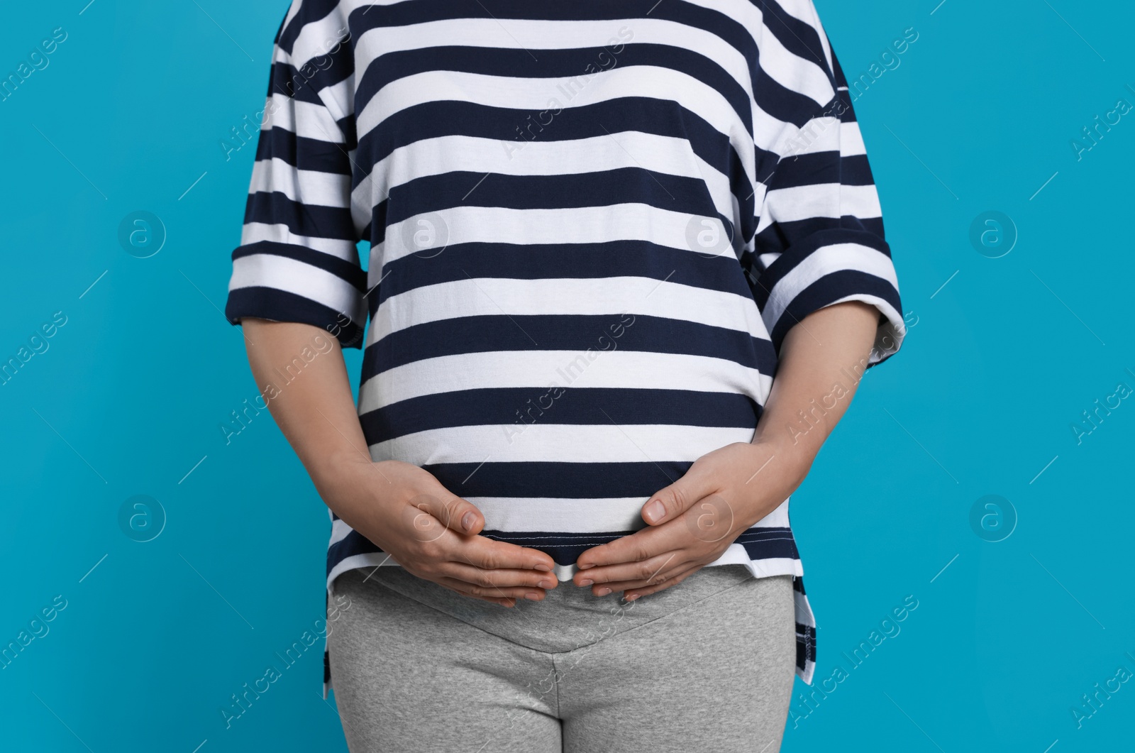 Photo of Pregnant woman on light blue background, closeup