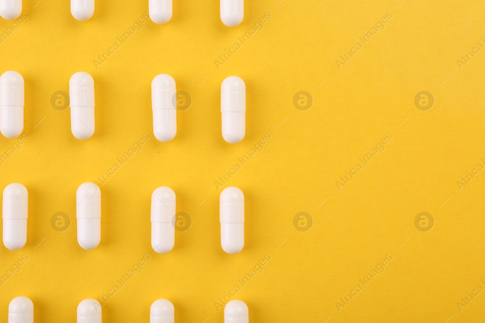 Photo of Many vitamin capsules on orange background, flat lay. Space for text