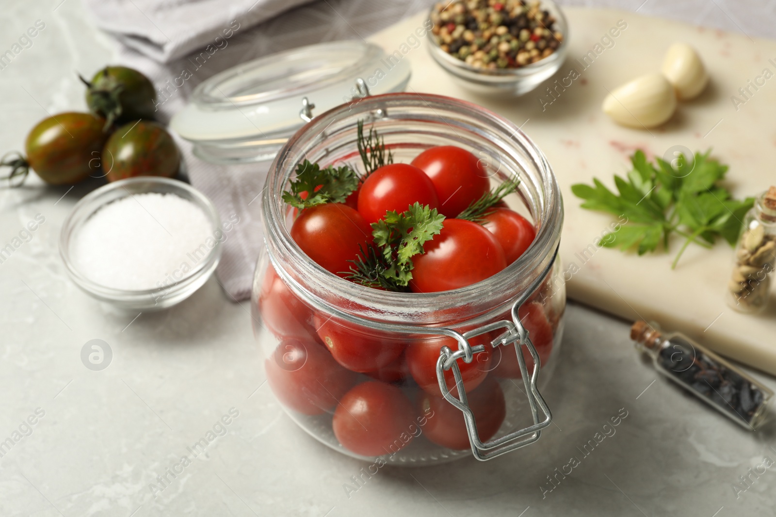 Photo of Pickling jar with fresh ripe cherry tomatoes and spices on grey table