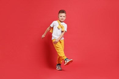 Photo of Happy little boy dancing on red background