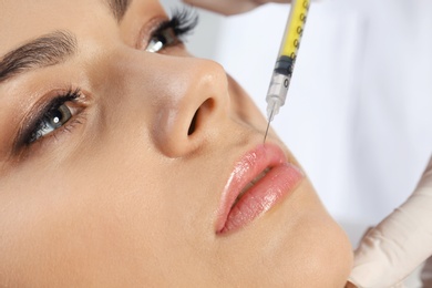 Photo of Young woman getting lips injection in clinic, closeup. Cosmetic surgery