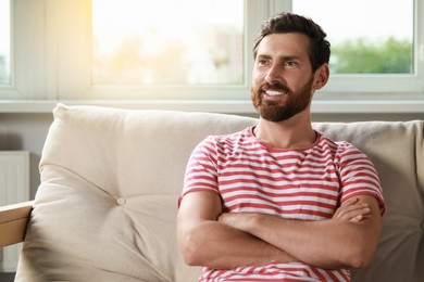 Portrait of handsome bearded man on sofa at home, space for text