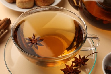 Aromatic tea with anise stars on beige background, closeup