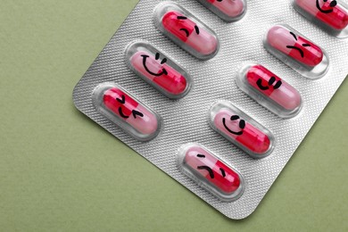 Photo of Antidepressants with different emoticons on light green background, top view